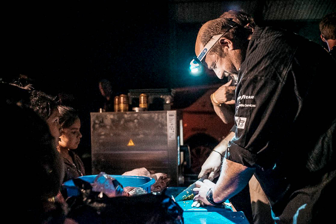 Réne Linke - chef of the Land Rover Experience Tour - cutting vegetables at night wearing a headlight