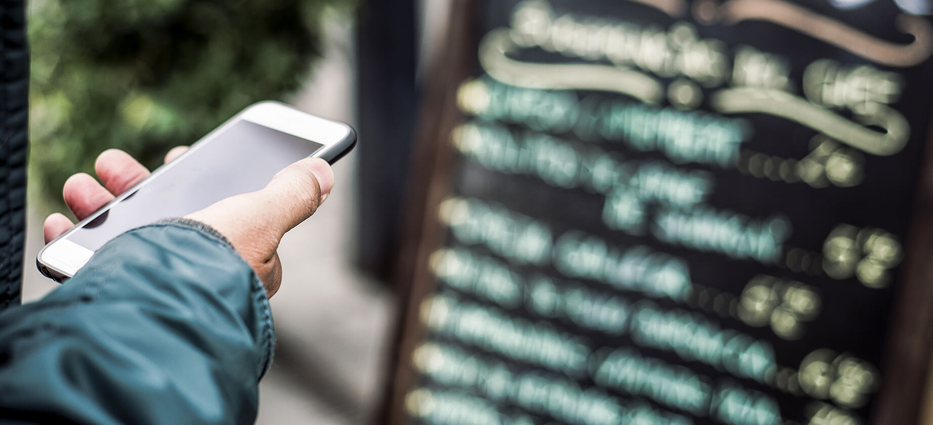 man checking restaurant reviews on Yelp or Google in front of a written menu.