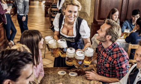 Junge Bedienung bringt einer jungen Gruppe von Menschen Bier im Hofbräu - eines der bekanntesten bayerischen Restaurants.