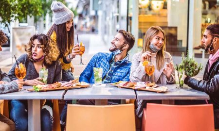 Young group of people enjoy sitting in a restaurant albeit it is outdoor.