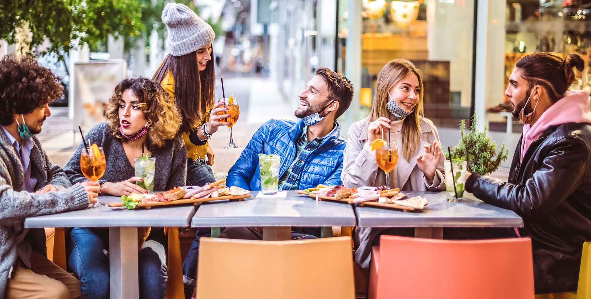 Young group of people enjoy sitting in a restaurant albeit it is outdoor.