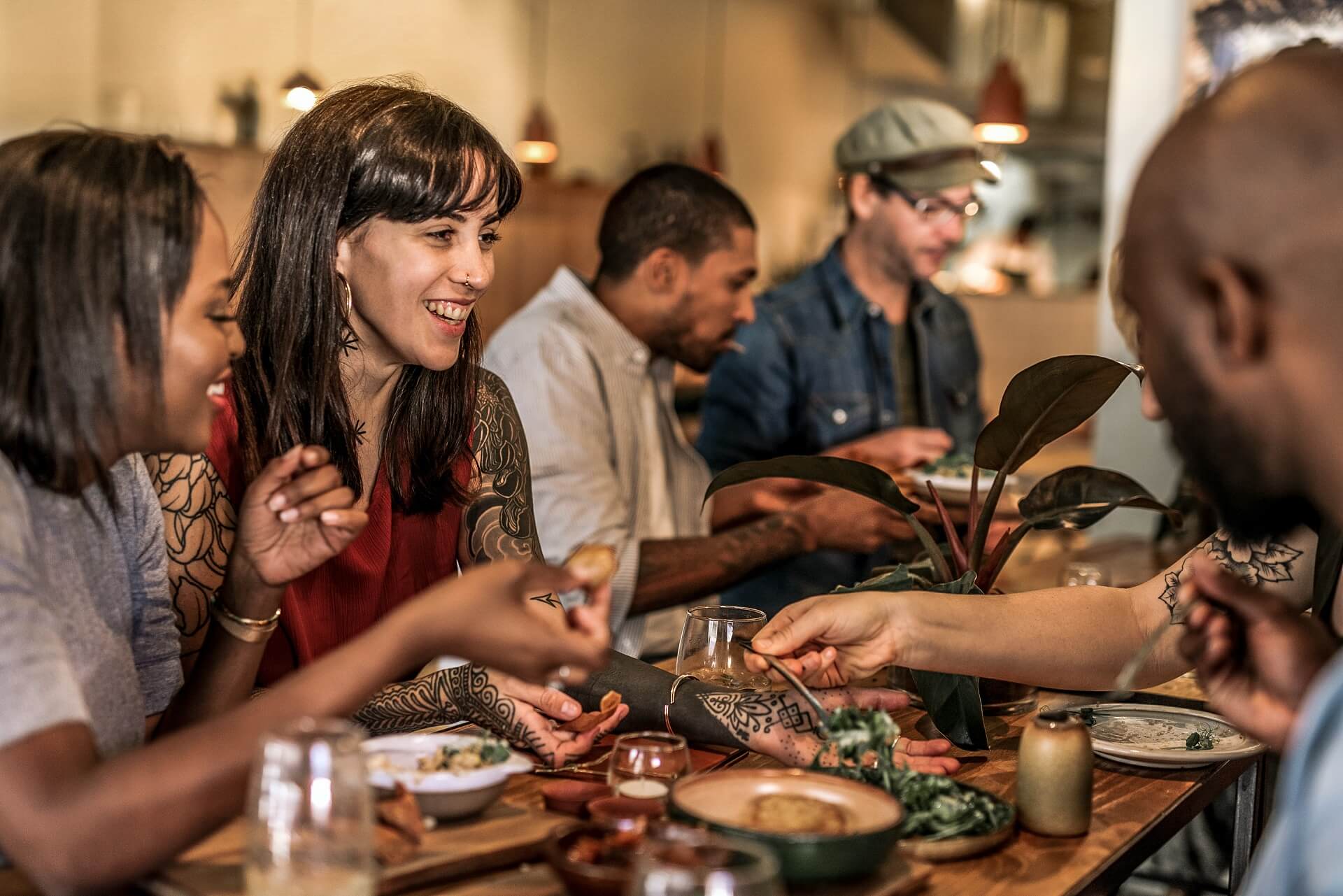 Junge Menschen sitzen zusammen in einem Restaurant - werden solche Treffen in Zukunft online stattfinden?