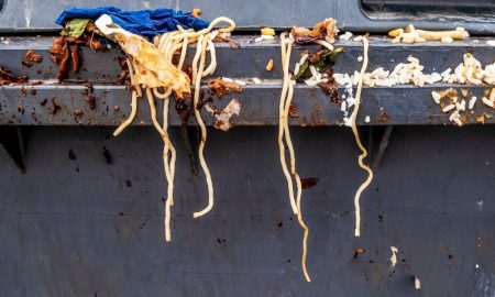 Food Waste: Spaghetti pasta and other waste food on a gray trash bin.