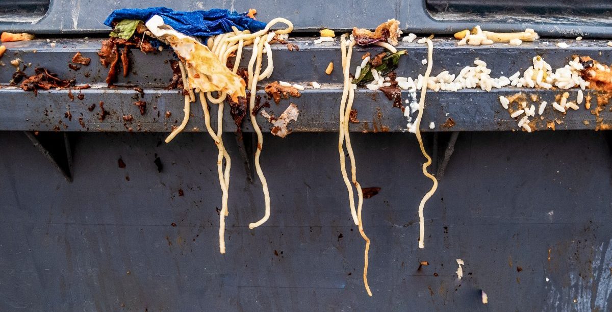 Food Waste: Spaghetti pasta and other waste food on a gray trash bin.