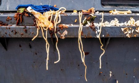 Spaghetti und andere Lebensmittelabfälle auf einem grauen Mülleimer.