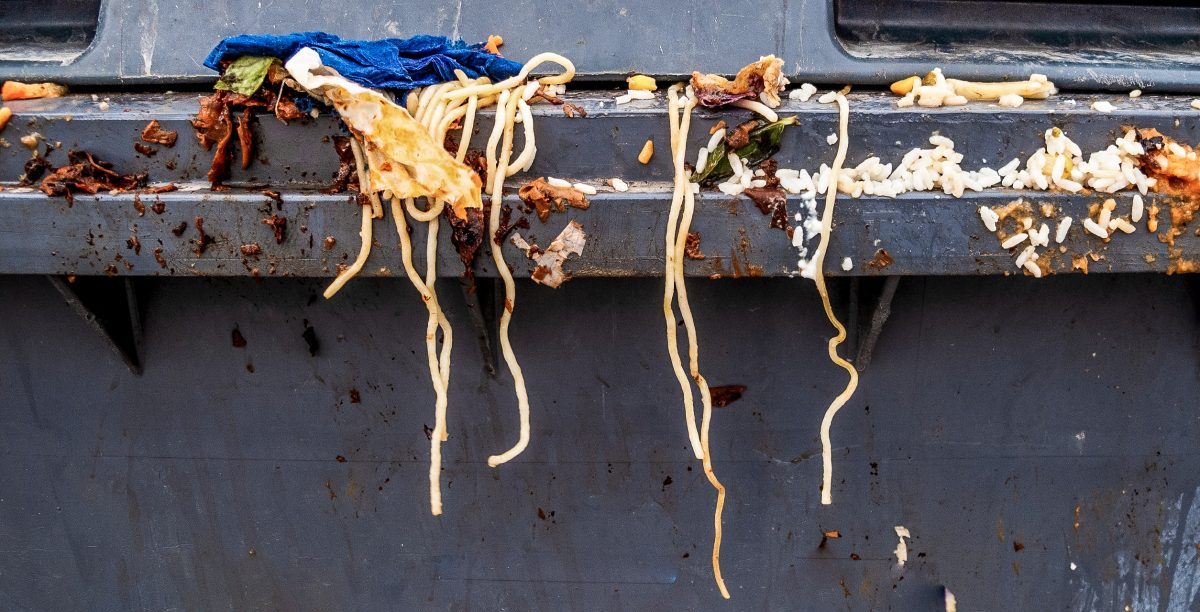 Spaghetti und andere Lebensmittelabfälle auf einem grauen Mülleimer.