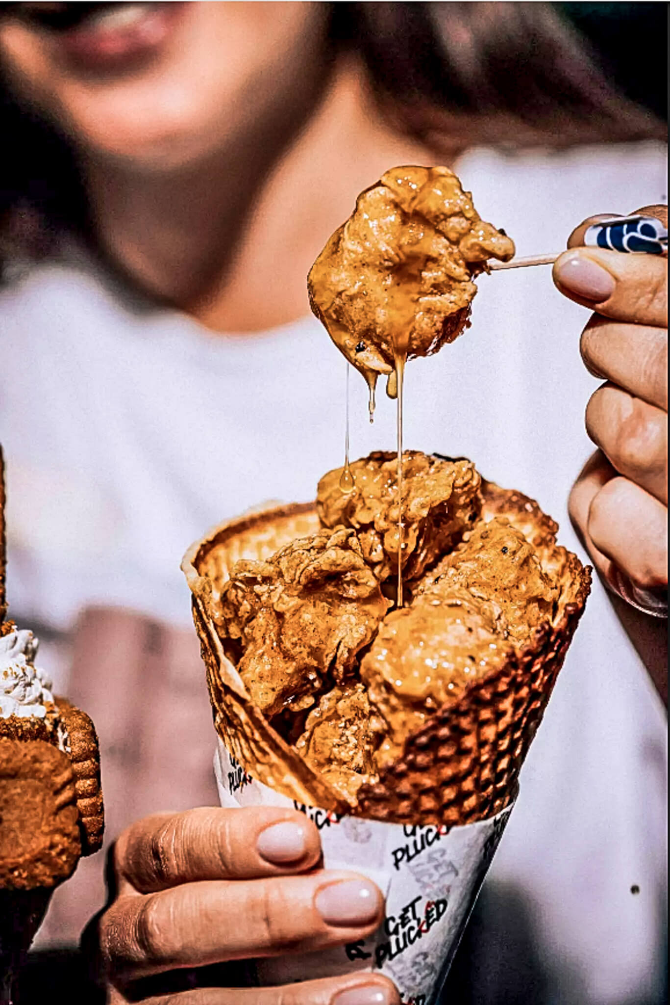 Frau die frittiertes veganes Hühnchen aus einer Waffel aufspießt