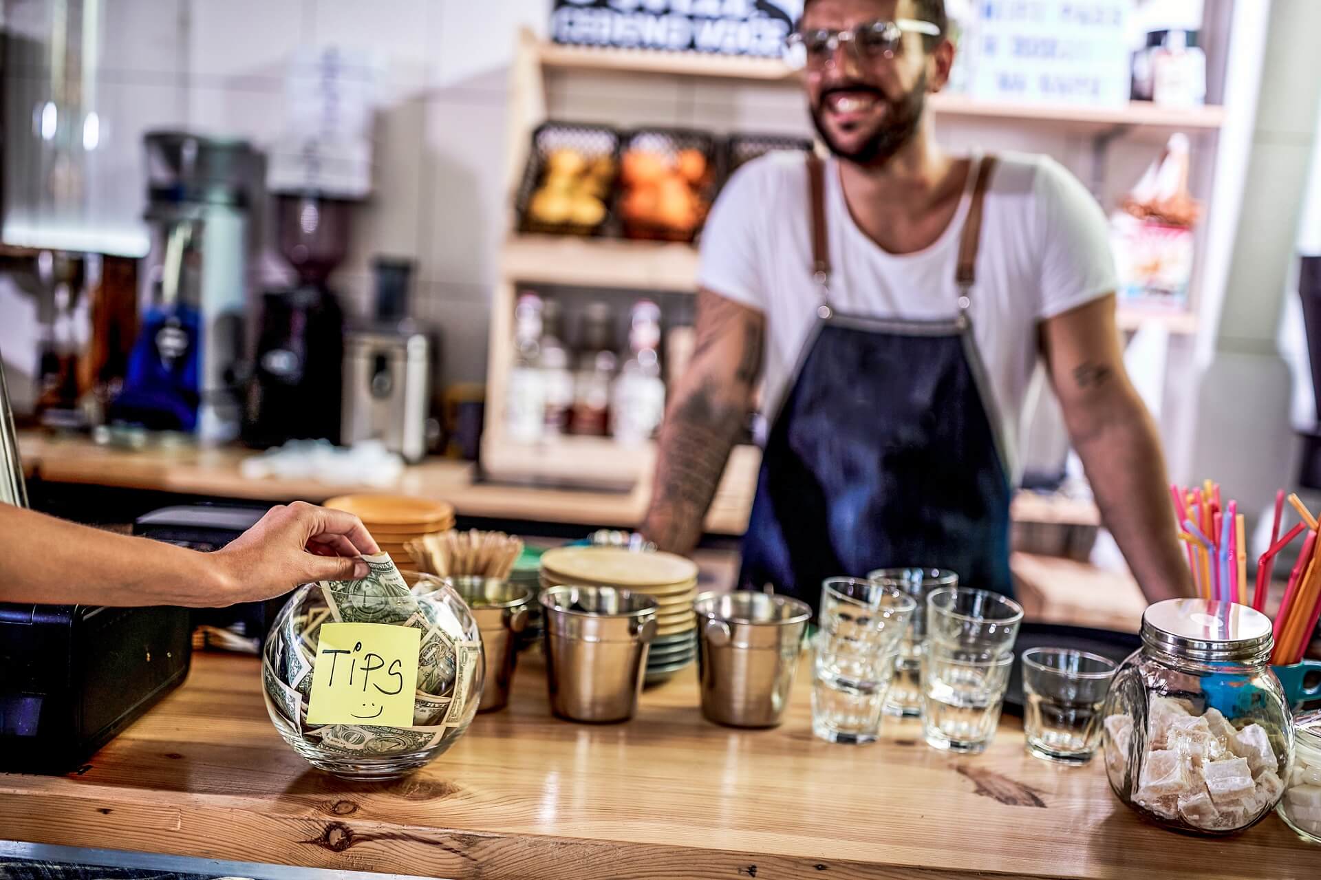 Kunde legt Geld in die Trinkgeldkasse eines Restaurants