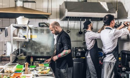 Professional cook holds kitchen utensil. Bearded chef in kitchen holds big  pot. Cook in white apron with pot. Master chef. Cooking, culinary, cuisine.  Food preparation concept. Chef man prepares meal. Stock Photo