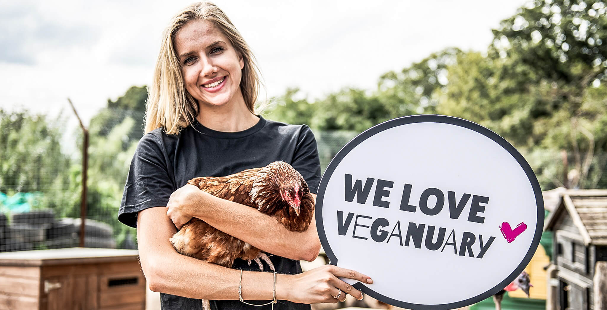 Mujer sosteniendo un pollo y el cartel "We love Veganuary" (Nos encanta el veganismo)