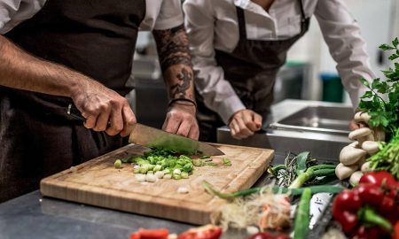 Two chefs, one is cutting vegetables, the other one checks