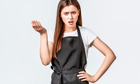 Young woman wearing a black apron complaining.
