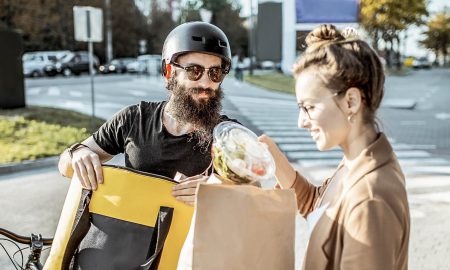 Kurier eines Essens-Lieferdienst übergibt Essen an junge Frau