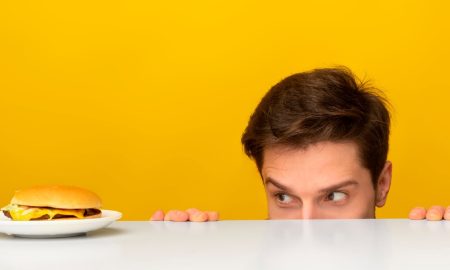 man looking at burger on plate