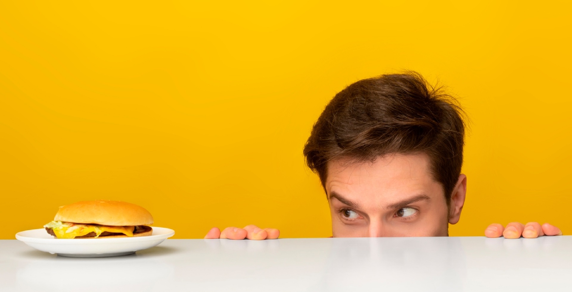 man looking at burger on plate