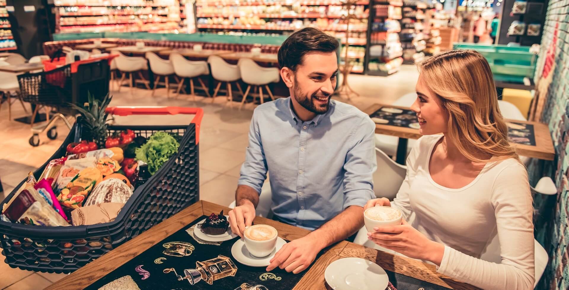 Pareja bebiendo un capuchino en un supermercado gastronómico