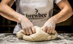 A brewbee employee kneads a pizza dough