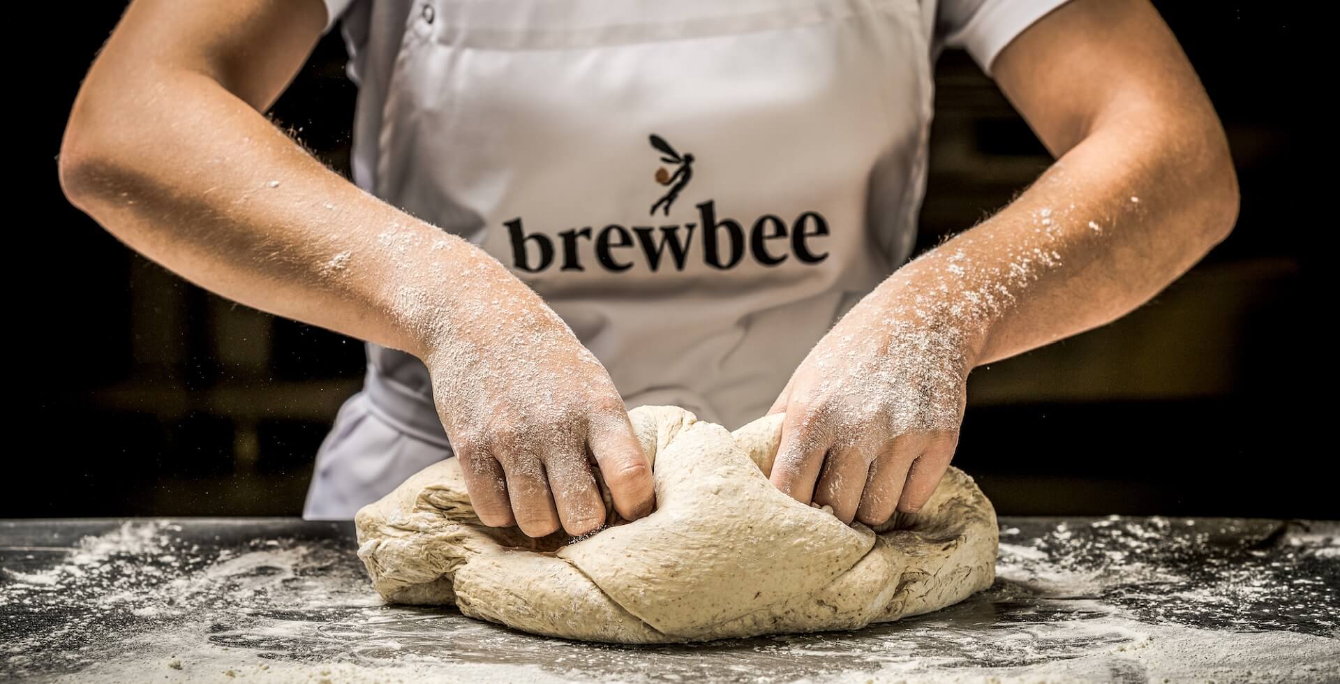 Un empleado de Brewbee amasa la masa de pizza