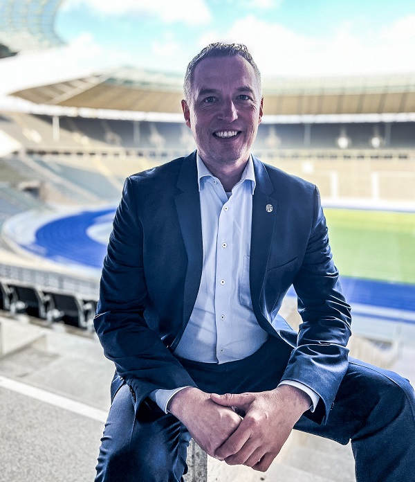 Markus Gollus sitzt auf einem Stuhl in einem Fußallstadion