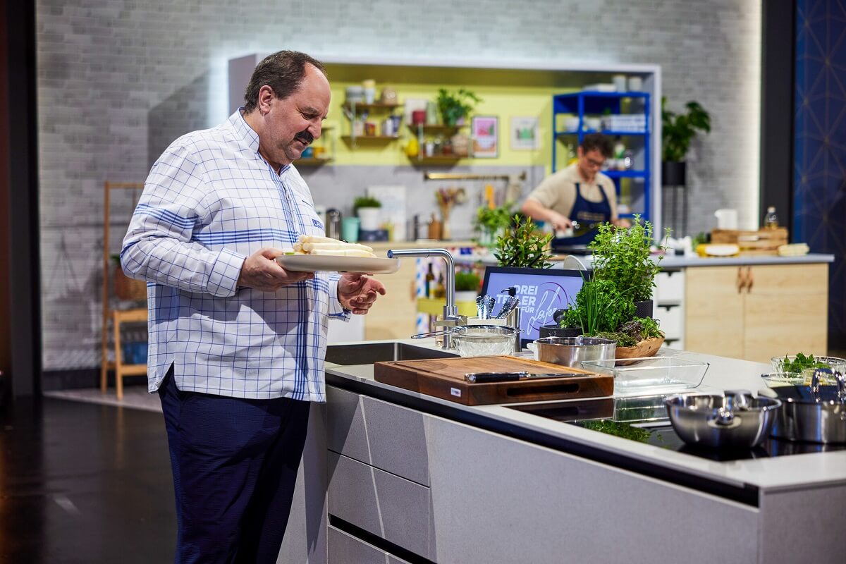 Johann Lafer bringt ein Gericht aus der Küche