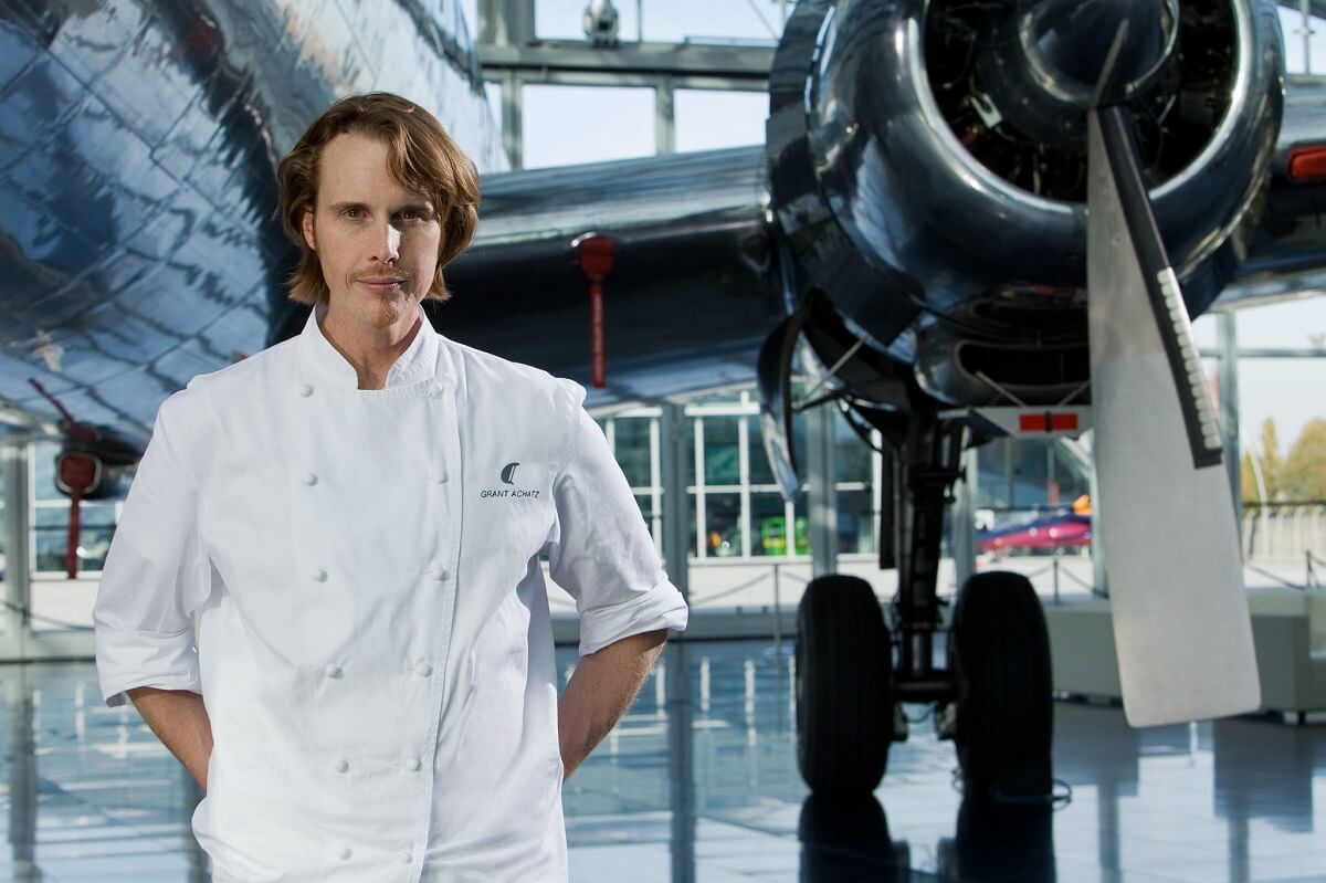 Grant Achatz in front of a small airplane in a chef's jacket