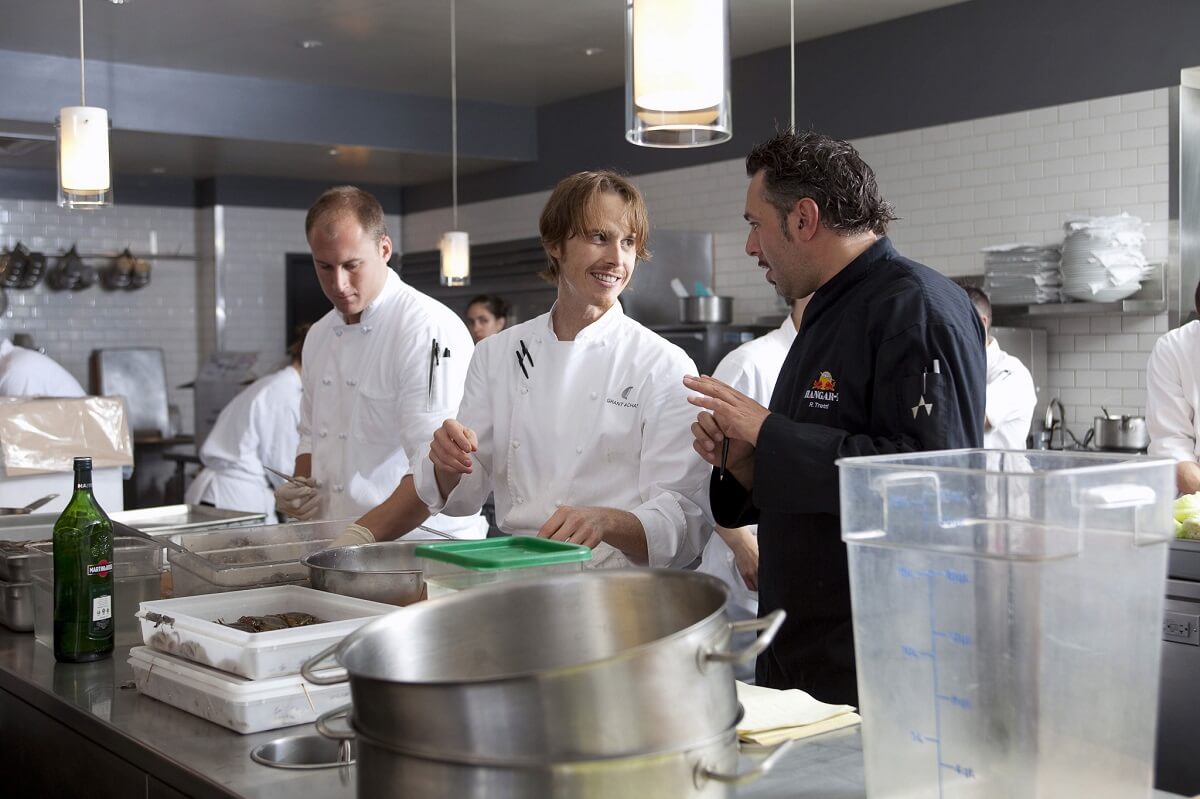 Grant Achatz in the kitchen, talking to several chefs