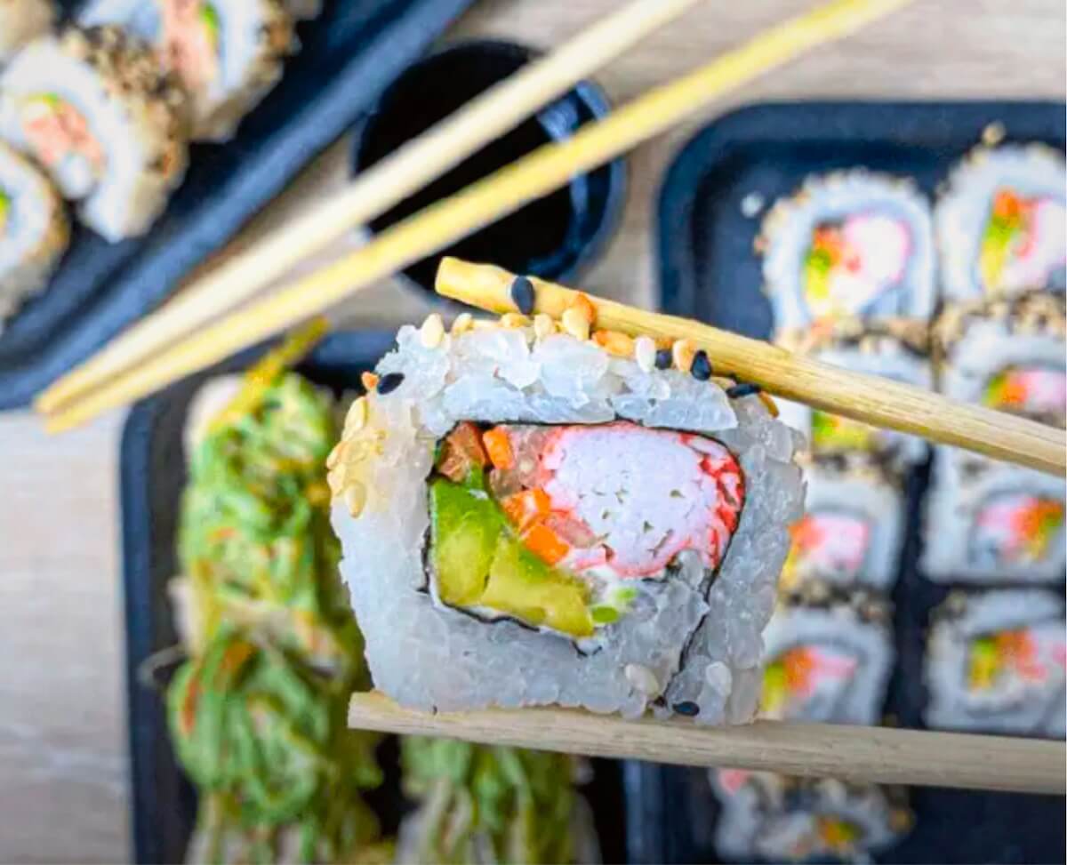 California Sushi Rolle zwischen zwei Stäbchen