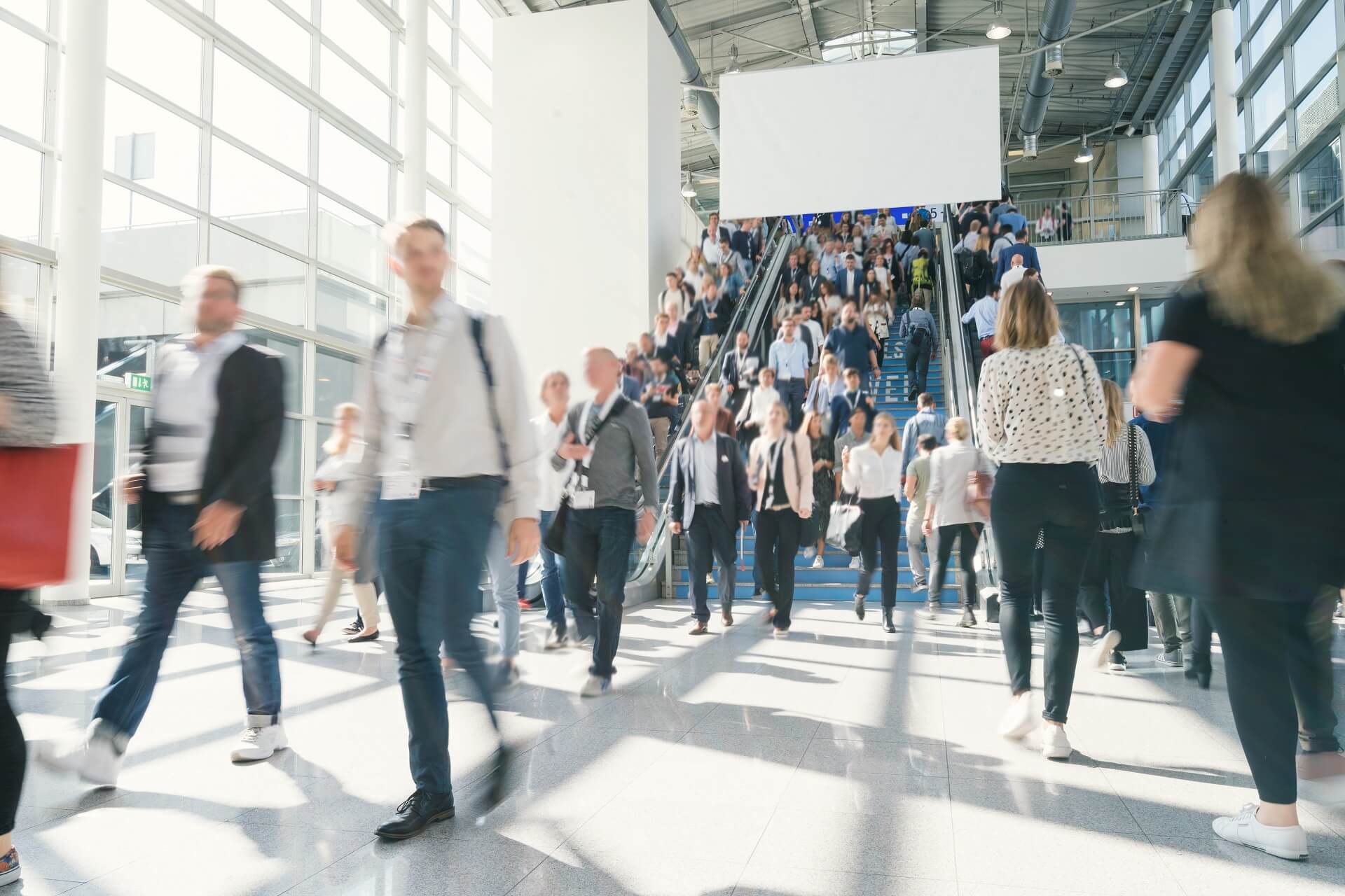 Menschen laufen in einer Messehalle