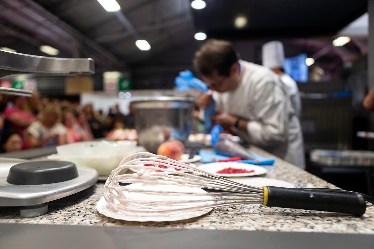Ein Patisserie-Stand auf einer Messe, mit einem Koch im Hintergrund