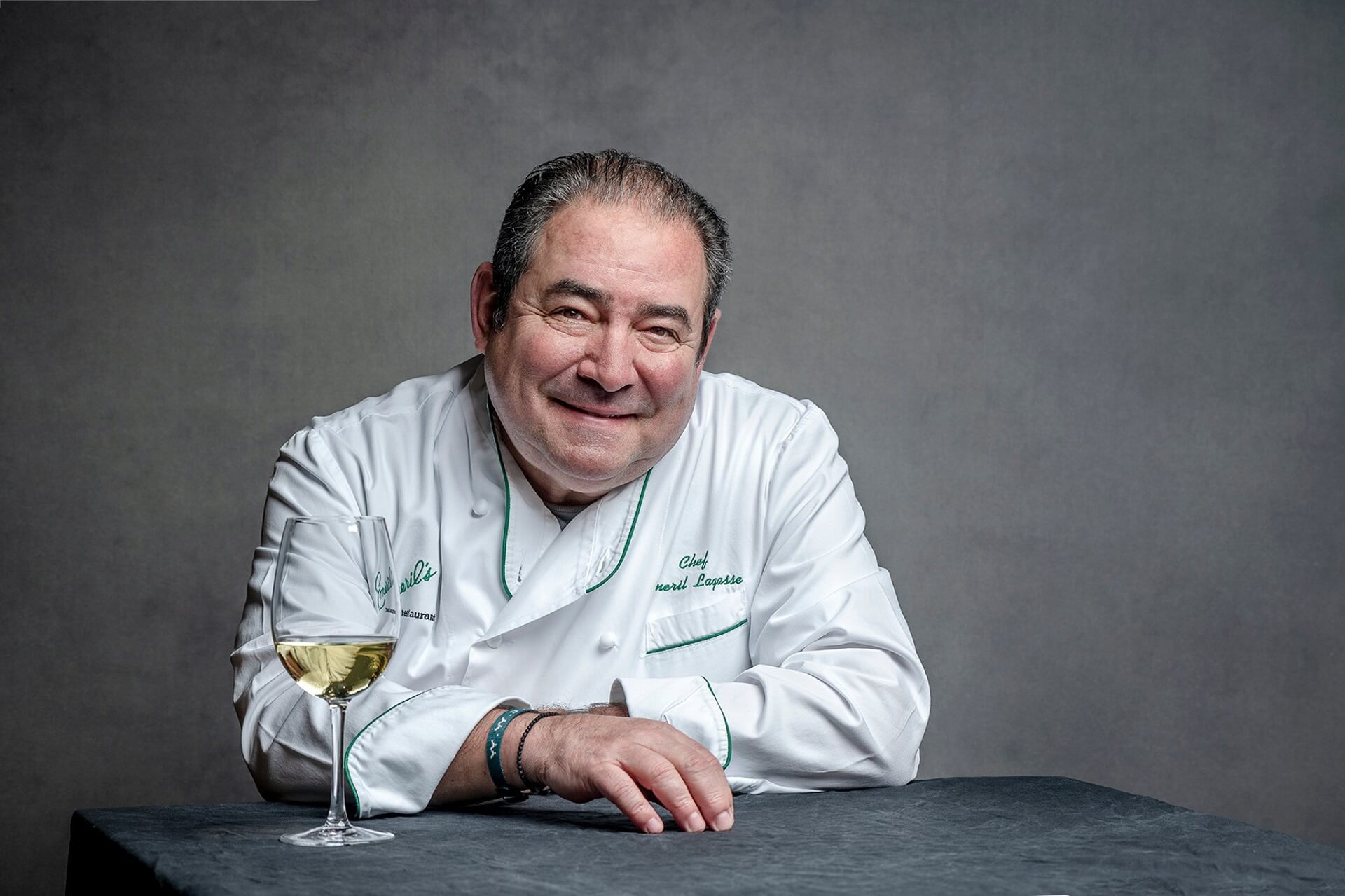 Portrait of Emeril Lagasse with a wine glass in front of him