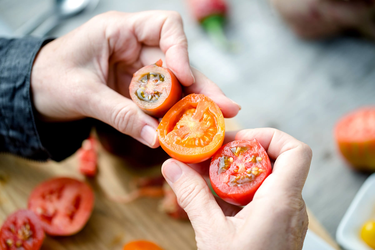 Halved tomatoes in hands. 